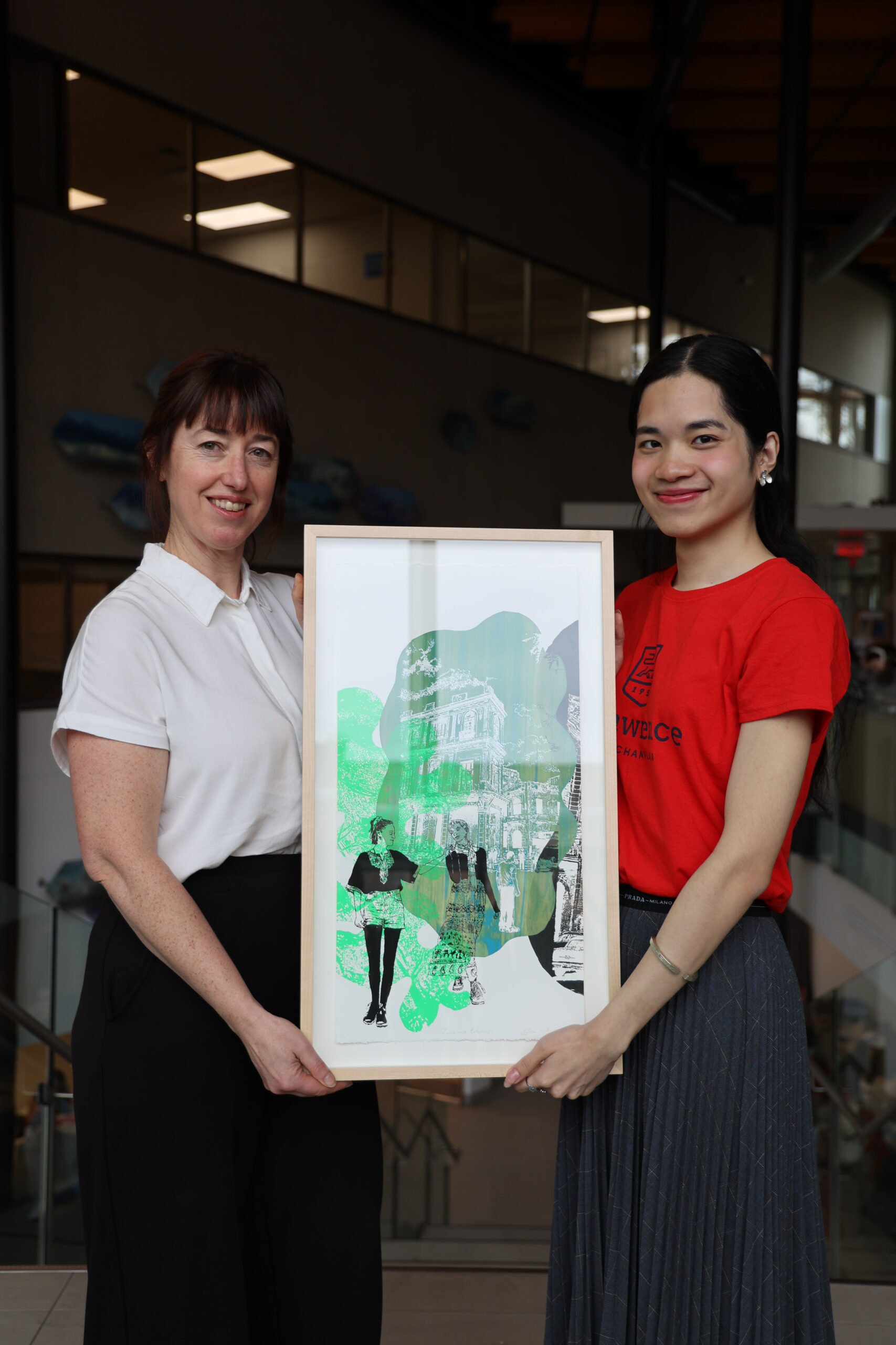 Bon Pham (right) presents Nicole-Anne Daigle with her prize, a painting by Tanya Morand.