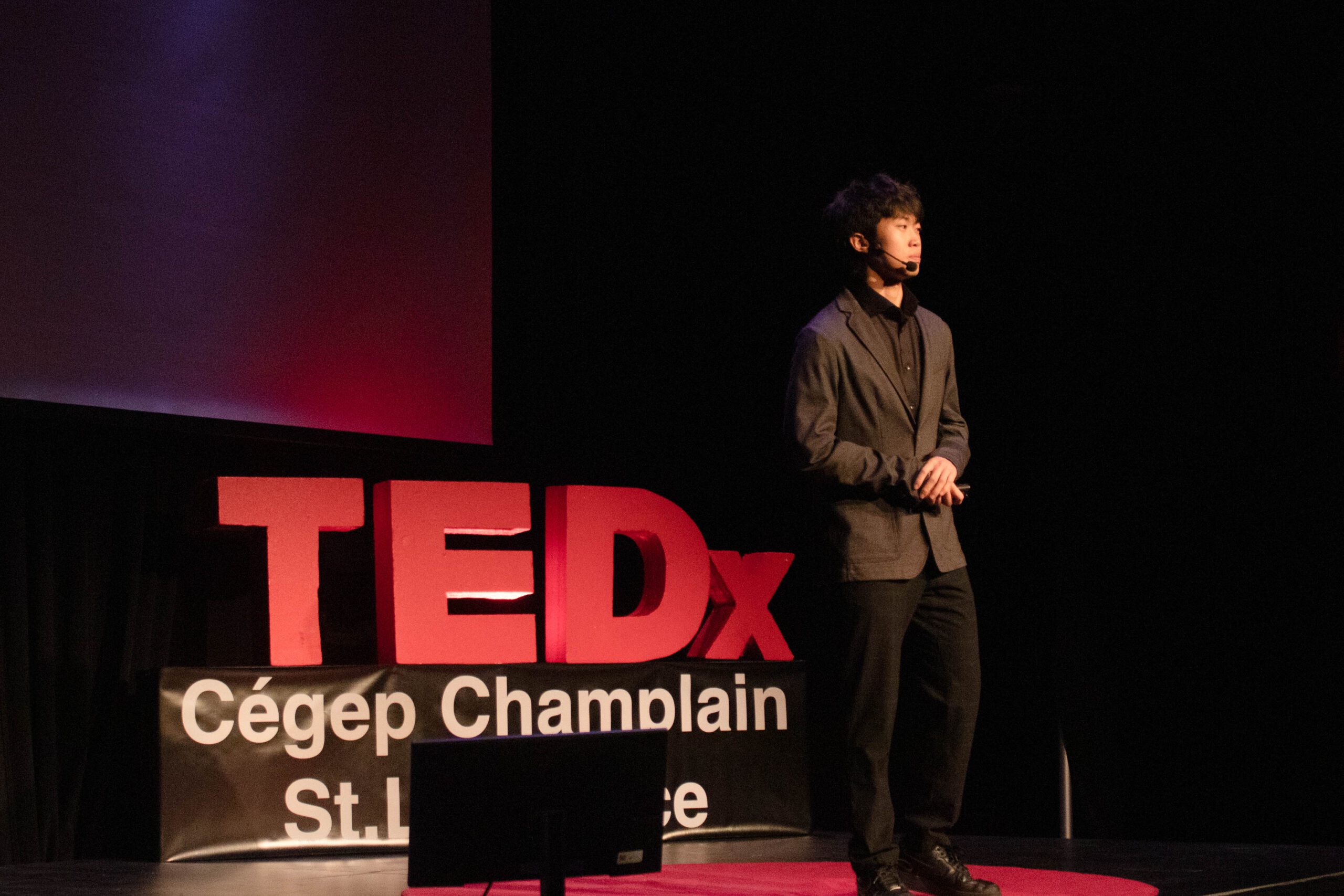 Student gives a talk in front of the TEDx sign