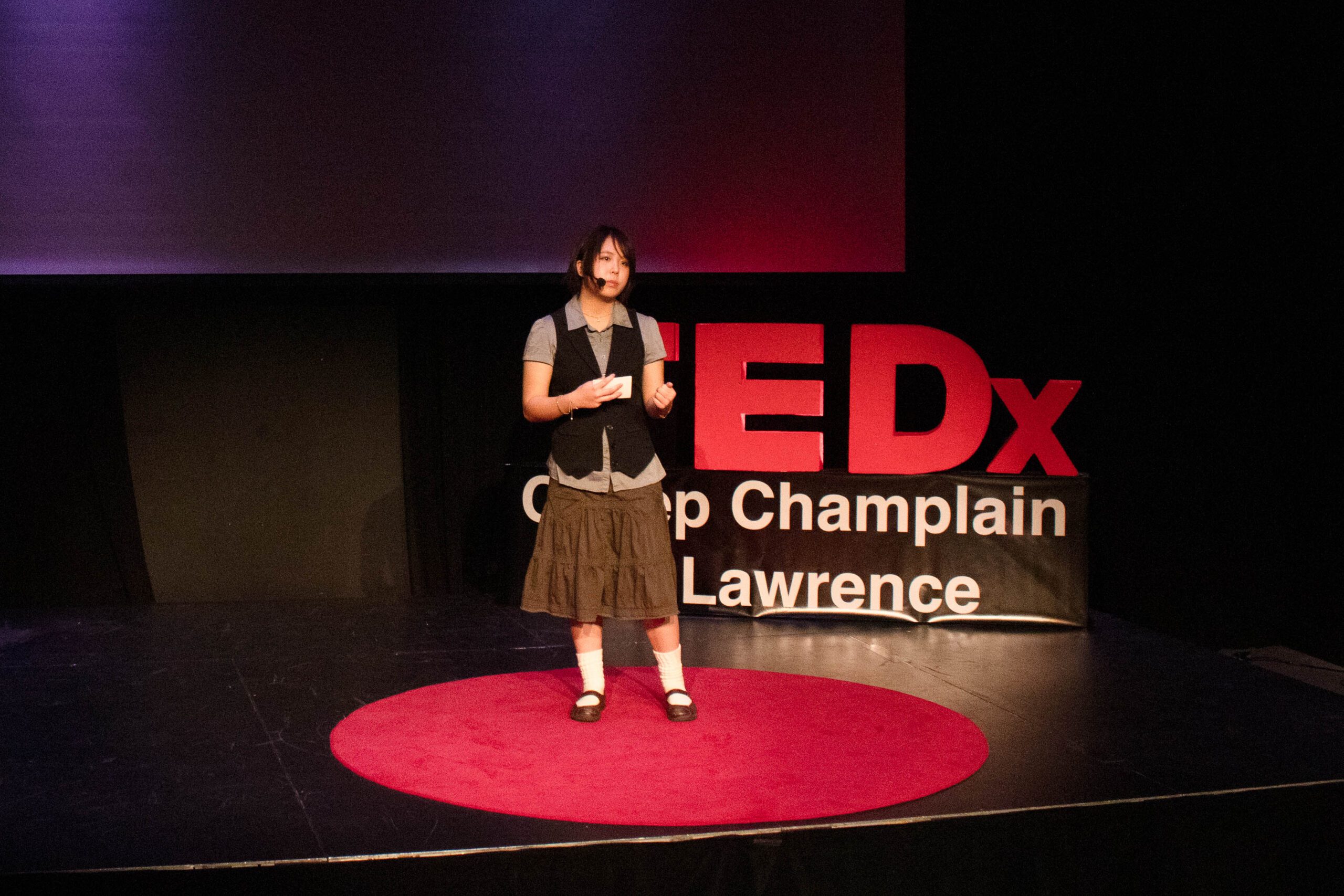 Student gives a talk in front of the TEDx sign